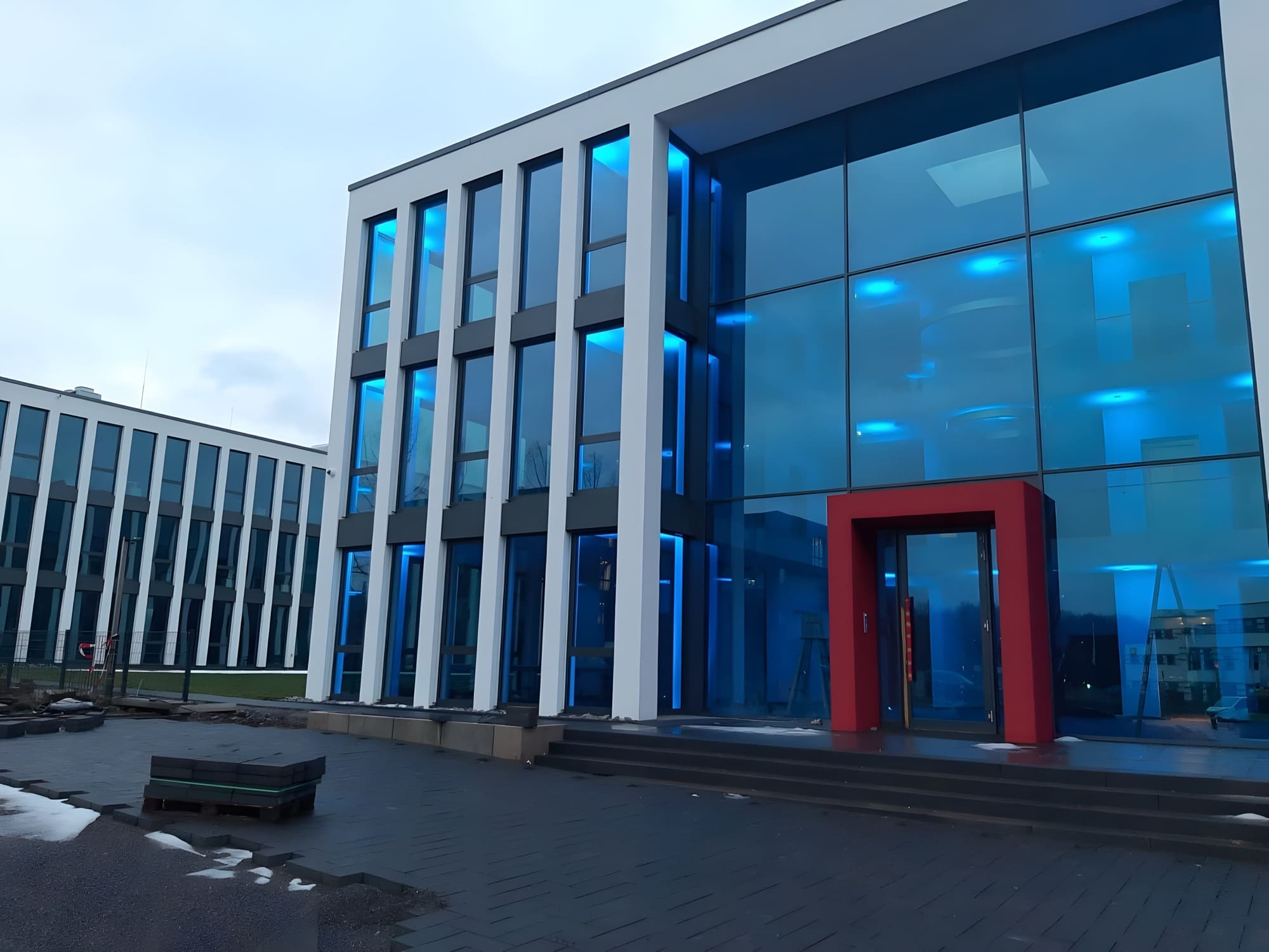Modernes Glas-Bürogebäude mit warmer Objektbeleuchtung in der blauen Dämmerung