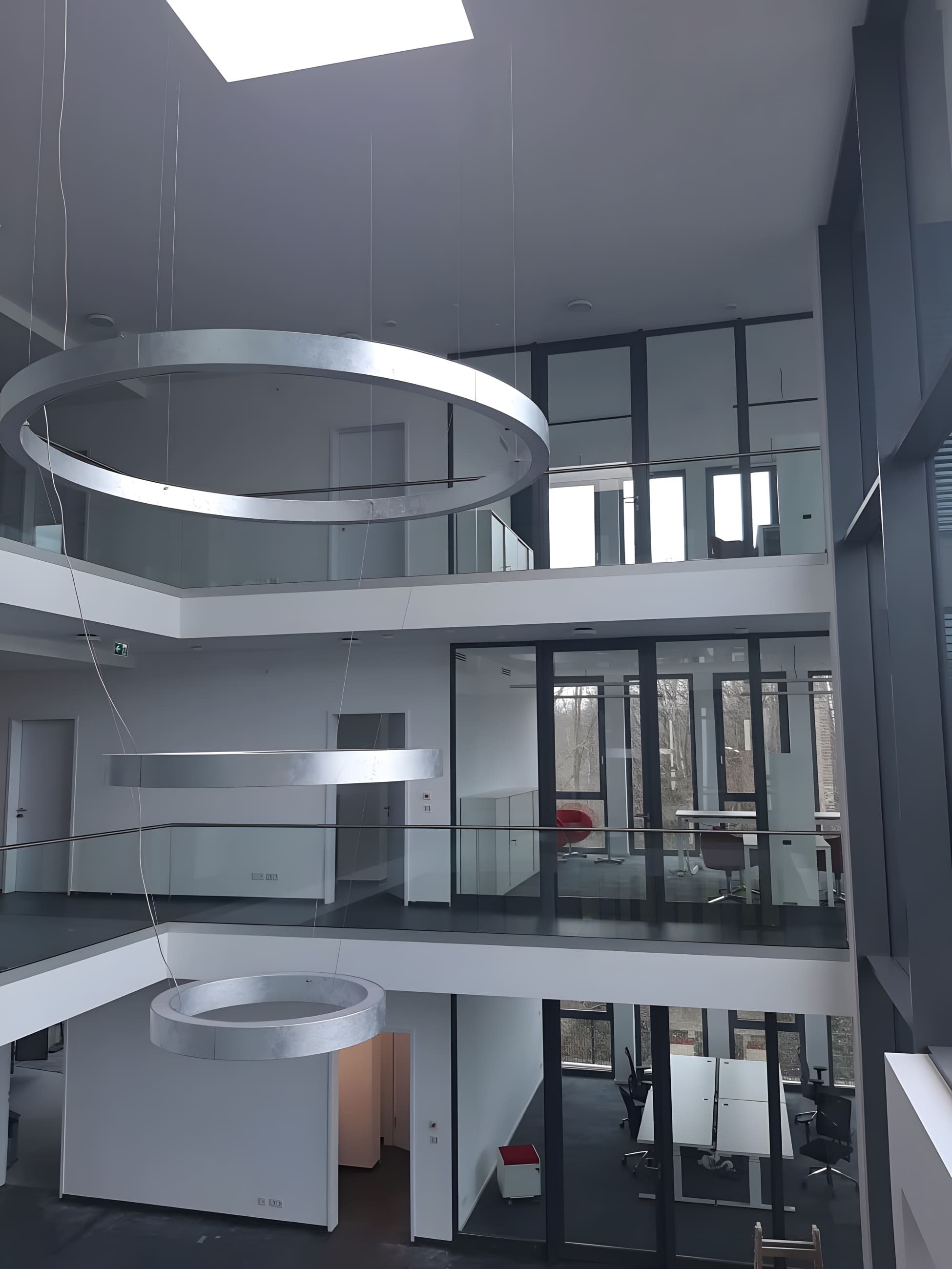 Atrium eines modernen Bürogebäudes mit Ring-Pendelleuchten — Elektro- und Lichtplanung für anspruchsvolle Bauprojekte